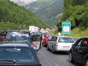 Stau auf einer Autobahn in den Bergen - einige Autotüren und Fenster stehen offen.
